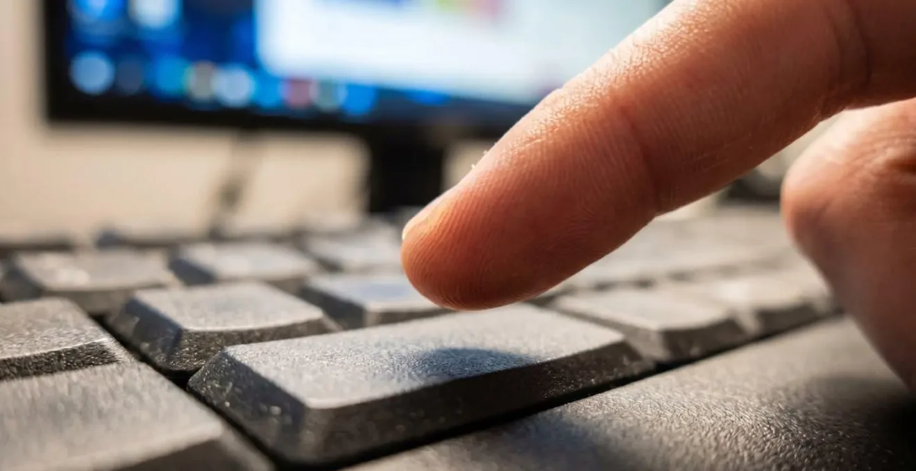 Vue macro d'un écran d'ordinateur montrant un formulaire avec des champs flous et une main qui hésite
